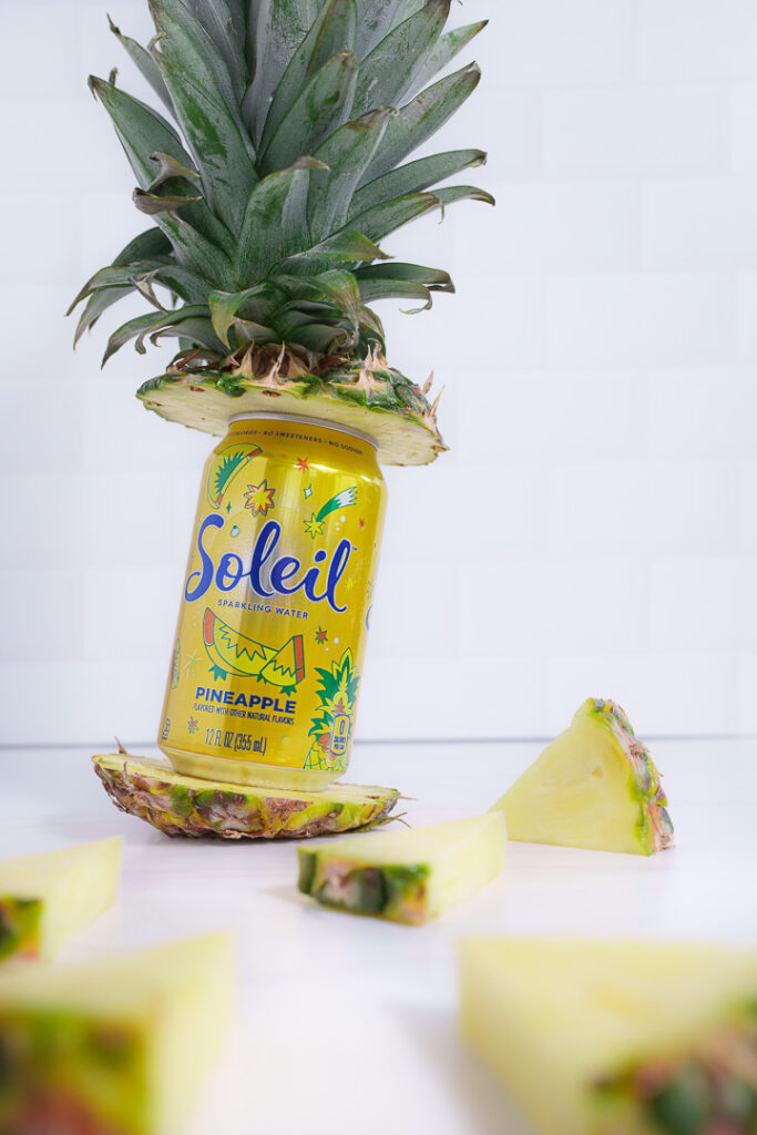7 Ways a Brand Photoshoot Can Save You Time Creating Social Media Content 8 Yellow can of Soleil propped between the top and bottom of a cut pineapple.