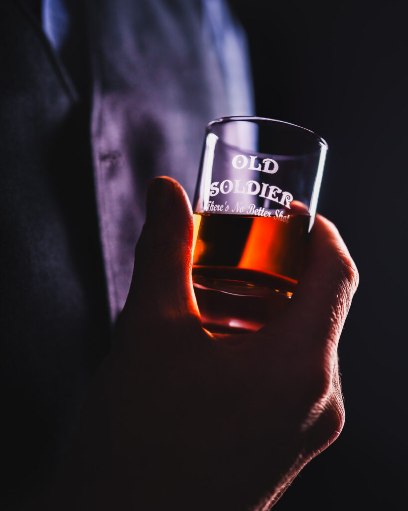 A glass of Old Soldier bourbon is shown in a dark and moody elevated style