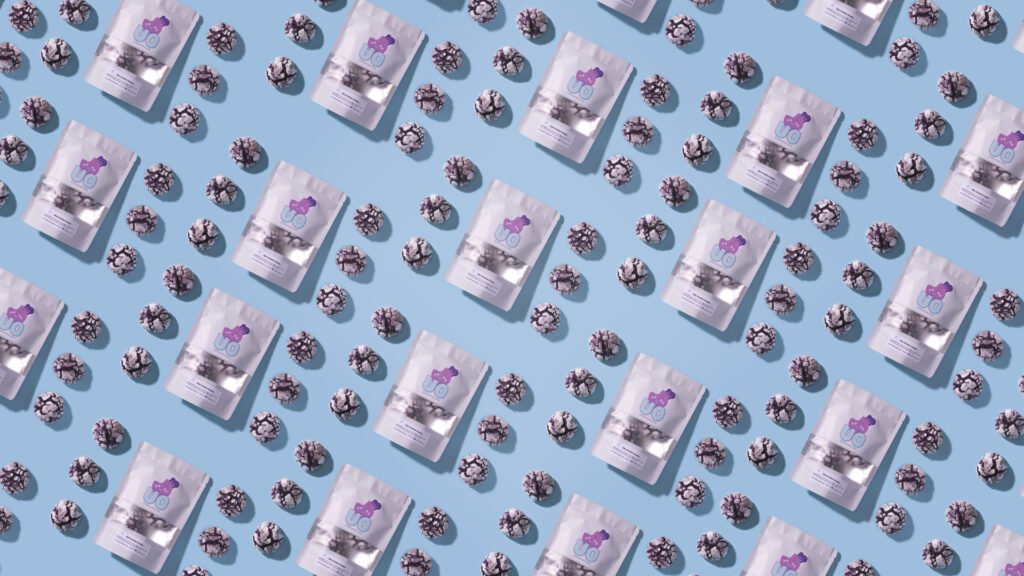 Seattle Brand Photography. Top-down perspective of Ube Overload crinkle cookies with product packaging on a bright blue background showcasing the fresh crinkle cookies.