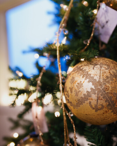 Hanging the ornament on the tree brings the brand to life in a festive context, creating connection, relevance, and visual storytelling that resonates with the audience. An ornament sits on the pine branches of the Christmas tree in House & Hazel