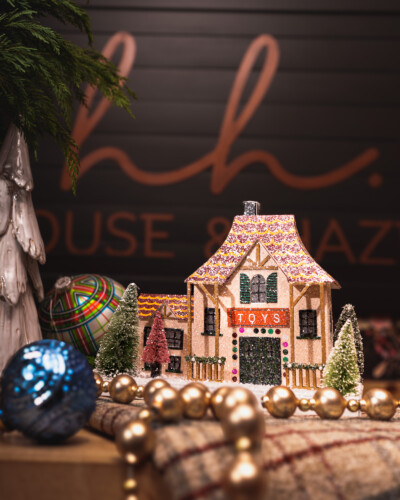 Showcasing multiple products in front of House & Hazel’s branded sign tells a complete brand story in a single image. It reinforces recognition, highlights the range of offerings, and connects the viewer to the brand’s personality and identity. Christmas ornaments sit on the front counter of House & Hazel, showcasing the Toy shop house