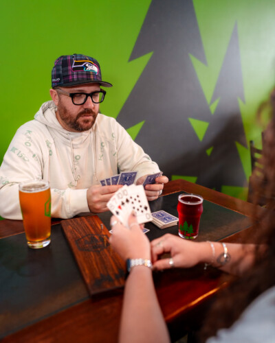 By capturing two people playing cards, this image emphasizes North 47’s commitment to community and fostering a welcoming, enjoyable space for connection - something that was important for them to capture during the collaboration. A visitor of North 47 brewing co plays cards at the table while drinking a beer during game night where community comes together