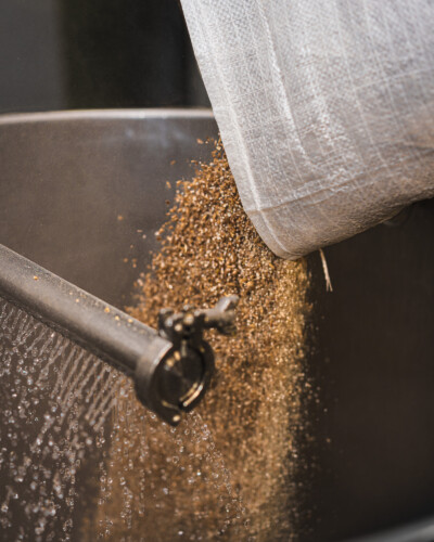 This detail shot of grains in motion emphasizes the craft behind every batch, reinforcing the brand’s commitment to quality and expertise. Detail shot of grains being added to begin the brew process