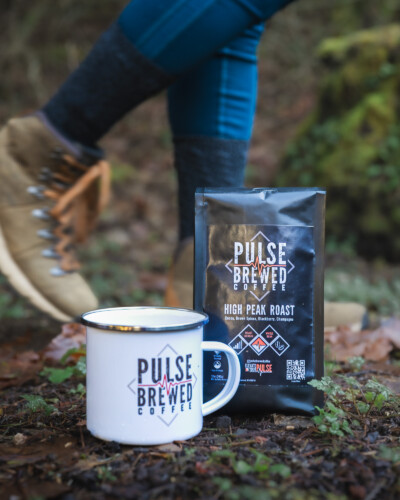 Using a slightly slower shutter, we add some motion to the hiker in the background, giving the image a sense of action that resonates with the message that Pulse Brewed Coffee wants to share Hiking boots walk past a bag of pulse brewed coffee with a coffee mug