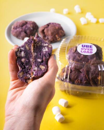 Adding a human element to showcase the ingredients in a clients products helps showcase the freshness and depth of the goods. Hand holds an Ube Overload cookie split in half to show the details of the cookie - including marshmallows, white chocolate, and nuts among that purple coloring