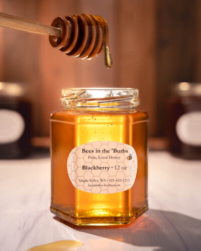Seattle product photography for Bees in the Burbs in Maple Valley. Raw, unfiltered Pacific Northwest honey gathered by bees in blackberry pollen - evergreen social media content for a small-batch local apiary. Seattle Product Photography - Raw Local Honey with drips coming off the honey dipper - Bees in the Burbs Maple Valley - Elemental Brand Photography