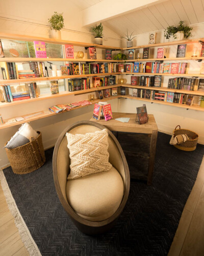 Seattle brand photography for Branches Booknook in Maple Valley, WA. A wider view of the booknook space inside House & Hazel captures the full atmosphere - cozy textures, layered styling, and natural light create a warm, browseable independent bookshop experience. Seattle Brand Photography - Branches Booknook Full Interior Space View with Books and Decor - Maple Valley, WA Inside House and Hazel - Elemental Brand Photography