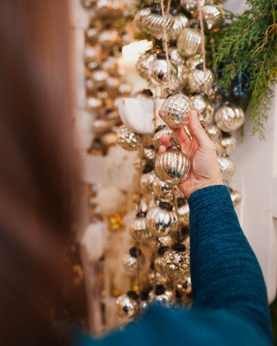 Seattle Brand Photography for House & Hazel in Maple Valley, WA. Christmas ornament garland styled in bright, warm light with a human element to add context for the viewer - social media content advertising the merchandise and experience of the local, small-business boutique Seattle Brand Photography - House & Hazel Home Boutique - Maple Valley, WA - Seasonal Christmas Display featuring Christmas Ornament Garland - Elemental Brand Photo