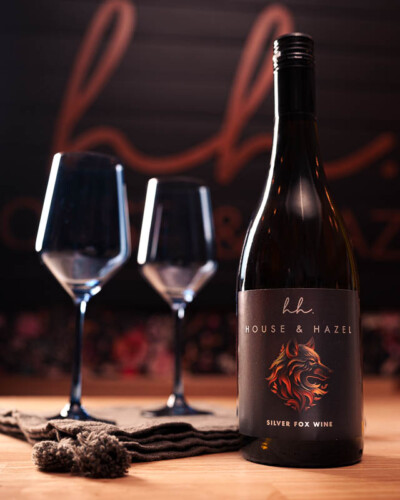 Seattle Brand Photography for House & Hazel in Maple Valley, WA. Staged bottle of boutique wine and glasses sold in the boutique with warm, targeted light on the product - social media content to showcase the local, small-batch wine pairing with the merchandise and branding of the local small-business Seattle Brand Photography - House & Hazel Home Boutique - Maple Valley, WA - custom, boutique wine crafted for the local small business - Elemental Brand Photo