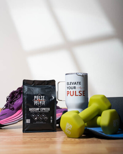 Seattle product photography for Pulse Brewed Coffee in Black Diamond, WA. Basecamp Espresso sits alongside workout gear with a window-like shadow across the wall behind - lifestyle product photography connecting this Pacific Northwest coffee brand to an active, energized audience. Seattle Product Photography - Pulse Brewed Coffee Basecamp Espresso with Window Shadow and Workout Gear - Active Lifestyle Coffee Brand - Black Diamond, WA - Elemental Brand Photography