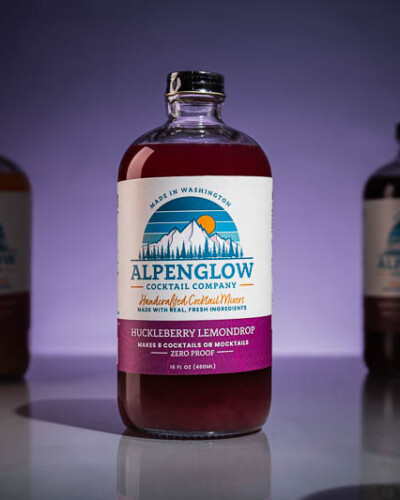 Seattle product photography for Alpenglow Cocktail Company in Issaquah, WA. Refined, mood-forward imagery showcasing craft cocktail mixers - evergreen hero banner image showing brand content for small batch beverage brands. Seattle Product Photography - huckleberry lemondrop cocktail mixer - Alpenglow Cocktail Company - Elemental Brand Photography