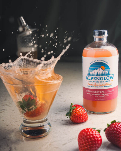 Seattle Product Photography for Alpenglow Cocktail Mixers in Issaquah. A strawberry splashes into a glass of strawberry basil smash for energy and action - evergreen social media content for growing local cocktail and mocktail mixer brand. Seattle Brand Photography - fresh local cocktail mixer with splash action - Alpenglow Cocktail in Issaquah WA - Elemental Brand Photography