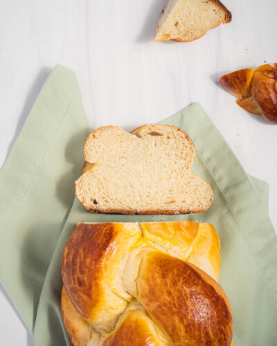 Seattle Product Photography for Emily's Bakery in Maple Valley, WA. Image features challah baked fresh in the local cottage bakery and shows the detail behind the woven loaf of bread. Evergreen images shot in soft, even lighting created for social media collaboration to hightlight the unique, high-quality challah bread available online & at the Maple Valley Farmer's market. Seattle Product Photography - Emily's Bakery - Maple Valley, WA - Challah bread flatlay - Elemental Brand Photography
